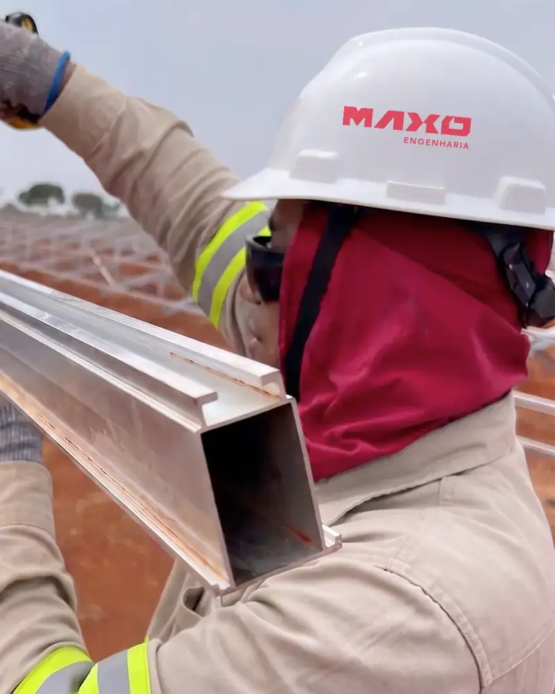 Técnico da Maxo Engenharia com equipamentos de proteção montando a estrutura de uma usina solar